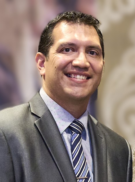 Smiling man in a grey suit with a striped tie.